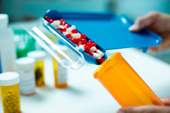 Des pilules rouges et blanches sont distribuées dans une bouteille de pilule orange.