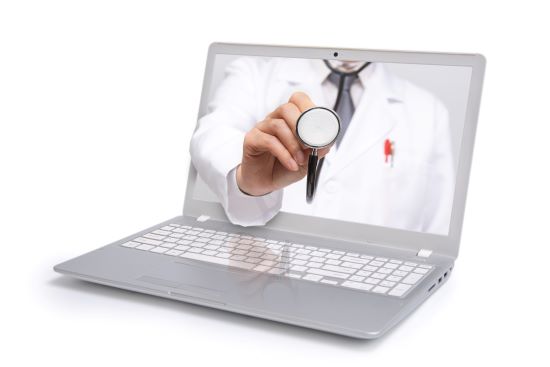 Laptop with a male doctor's hand holding a stethoscope reaching out of the screen to represent telemedicine.