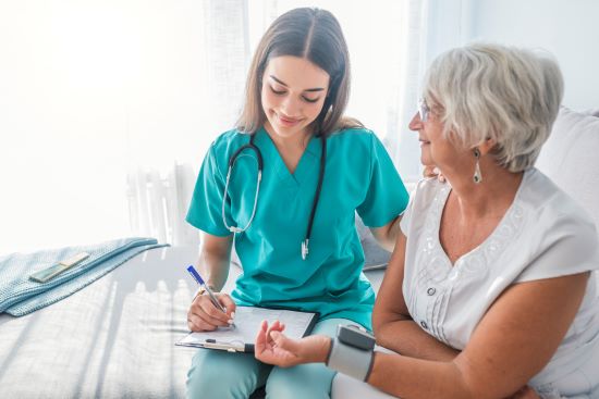 Young Caucasian nurse measuring elderly woman's blood pressure . 