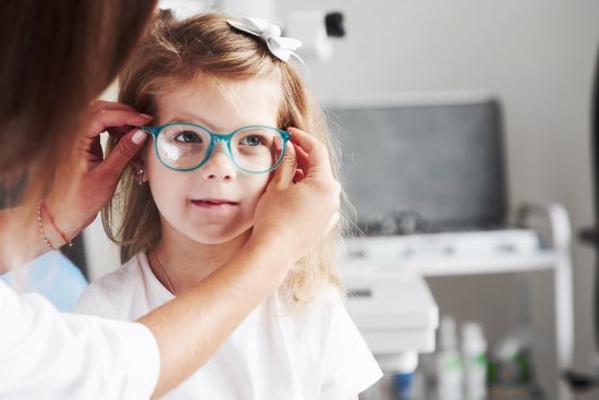  Nouveau look. Médecin donnant à l'enfant de nouvelles lunettes pour sa vision.