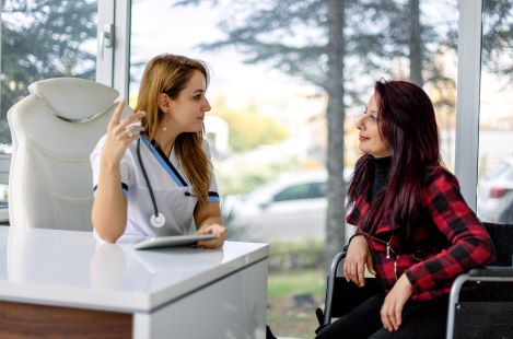 Female doctor explaining good medical results to her female patient who is in a in a wheelchair
