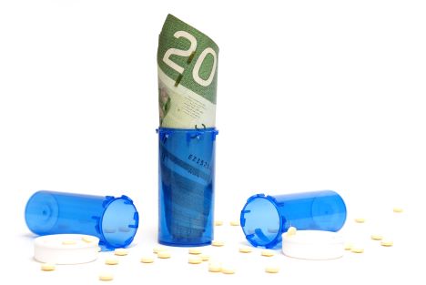 A conceptional photo of pills and money to represent the high cost of prescription drugs.