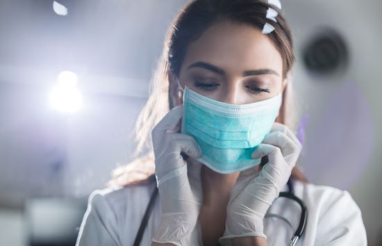 Young female doctor putting on protective mask