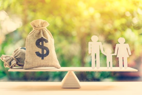 Health Care Spending Account savings for the family : Dollar or cash in hemp bags or burlap sacks and a white paper cut (dad, mom and son) on wood balance scale. Green nature background.