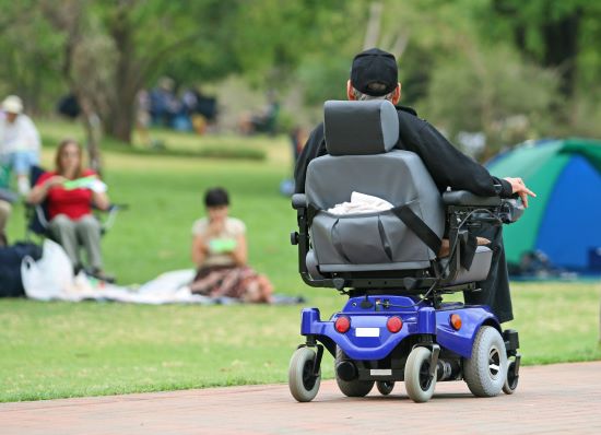 A man suffering from amyotrophic lateral sclerosis enjoying a ride in the park in his electric wheelchair.