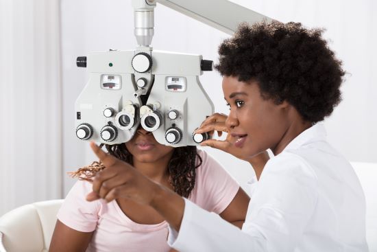 A Black Female Optometrist conducting a sight examination on a black female patient.