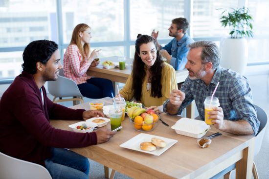 A group of employees, two males and female, enjoying a healthy lunch together in the company lunchroom. Their workplace health and welfare benefits help them manage their well-being.