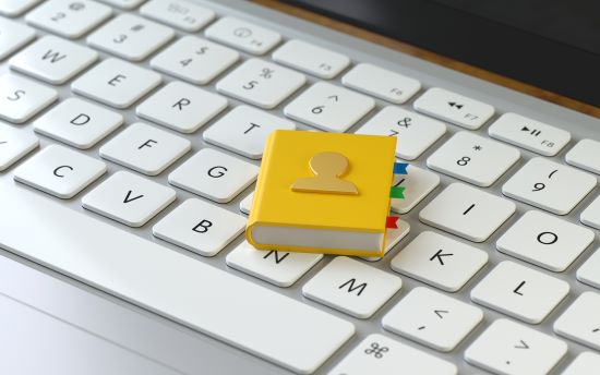 A yellow address book sitting on a white computer keyboard representing an online directory to search for doctors in British Columbia.