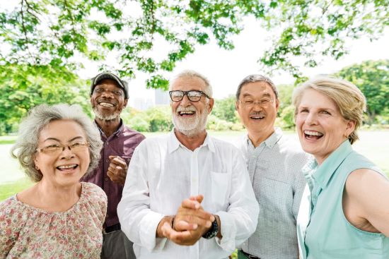 A group of seniors from diverse backgrounds standing outside on a nice day looking healthy and happy.