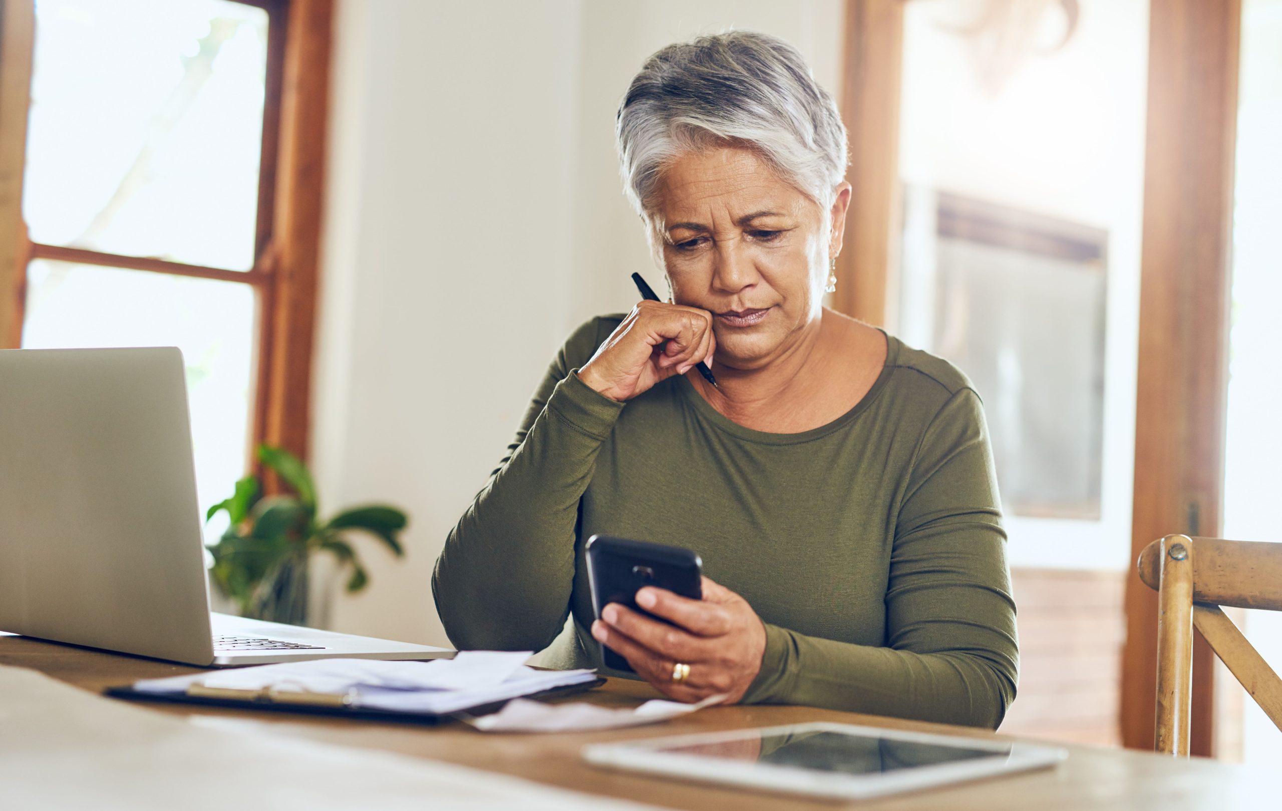 Older women going over her finances and looking at her phone.