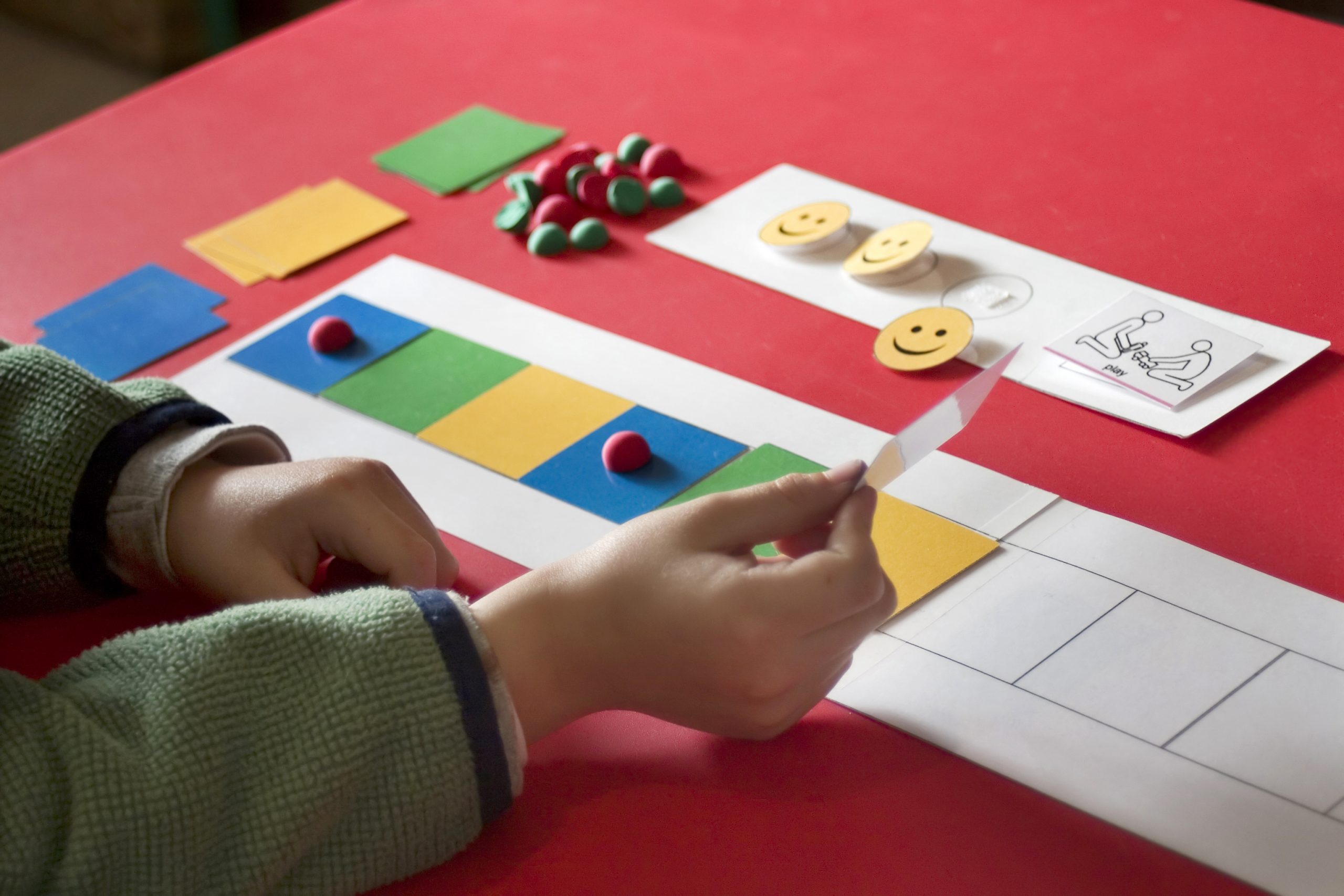 Autism therapy. A child's hand is visible as he tries to complete a cognitive puzzle as part of his one-on-one autism therapy. 