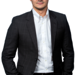 Photo of Eckler Principal Milos Gavrilovic. He is wearing a black jacket and pants, and is looking straight into the camera smiling.