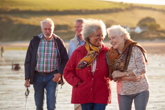 Two senior couples walking on a windy beach enjoying a relaxing day in life of retirement.